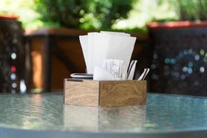caja con servilletas de papel sobre una mesa de vidrio, primer plano. parte del ajuste de la mesa café de verano al aire libre