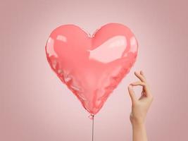 mano con un alfiler junto a un globo en forma de corazón foto