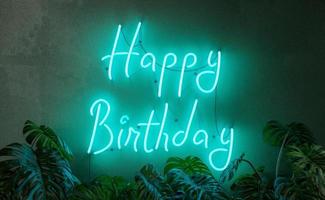 cartel de neón de feliz cumpleaños con plantas en el frente foto