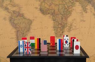 símbolos de países en el tablero de ajedrez contra el fondo del mapa político del mundo. juegos politicos foto