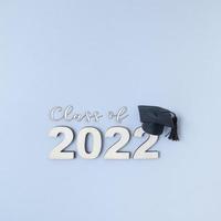 Class of 2022 wearing graduate hat on wooden number 2022 on grey background with copy space photo