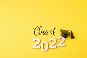 clase de 2022 con sombrero graduado y número de madera 2022 sobre fondo amarillo con brillo foto