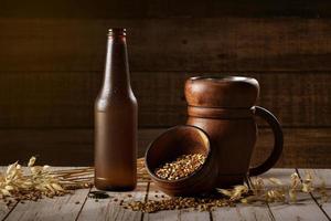 Glass and bottle of beer, ears of barley on wooden background. Ale. photo