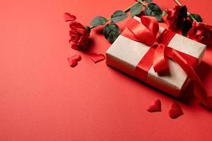 Valentines Day gifts, roses and confetti on red backdrop, copy space photo