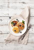 Cottage cheese pancakes served with curd and blueberries, top view flat lay on wooden background photo