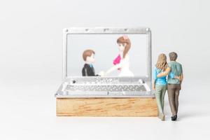 gente en miniatura novia y novio boda virtual en la pantalla de la computadora foto