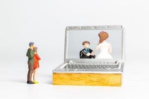 Miniature people Bride and groom virtual wedding on computer screen photo