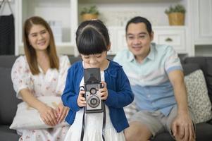 a cute Asian daughter holding camera is taking photos of her parents at home on weekends.