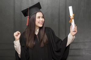 retrato de mujer joven en bata de graduación sonriendo y animando sobre fondo negro foto