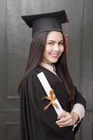 retrato de mujer joven en bata de graduación sonriendo y animando sobre fondo negro foto