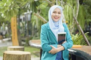 mujer musulmana con hiyab está trabajando con una computadora portátil en una cafetería foto