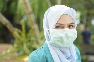 Muslim woman with hijab is wearing face mask outdoors photo