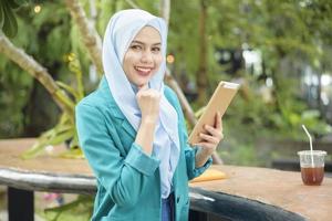 mujer musulmana con hiyab está trabajando con una computadora portátil en una cafetería foto