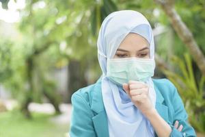 Muslim woman with hijab is wearing face mask outdoors photo