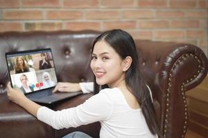 una joven está mirando la pantalla de su computadora mientras se encuentra en una reunión de negocios a través de una aplicación de videoconferencia foto