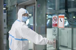 An Asian man is wearing ppe suit in airport elevator , Safety travel , covid-19 protection , social distancing concept photo