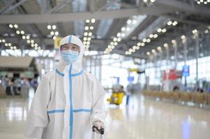 An Asian man is wearing ppe suit in International airport , Safety travel , covid-19 protection , social distancing concept photo