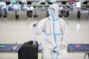 An Asian man is wearing ppe suit in International airport , Safety travel , covid-19 protection , social distancing concept photo