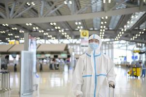 An Asian man is wearing ppe suit in International airport , Safety travel , covid-19 protection , social distancing concept photo