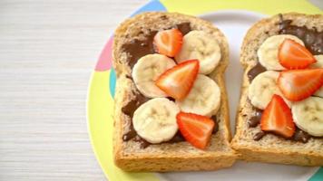 pain de blé entier grillé avec banane fraîche, fraise et chocolat pour le petit déjeuner video