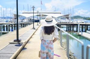 Excited tourist in white hat enjoying and standing on the dock with luxury yachts during summer photo