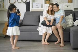 una linda hija asiática que sostiene una cámara está tomando fotos de sus padres en casa los fines de semana.