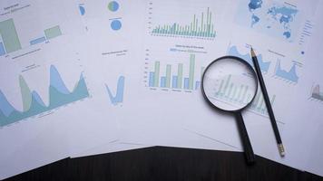 Magnifying glass and documents with analytics data lying on table photo