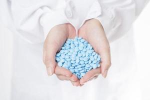 Close up doctor hand is holding pills on white background photo