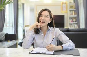 la vista de pantalla de la joven empresaria asiática está en línea usando una videoconferencia con socios o compañeros de trabajo desde su casa. foto