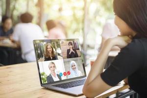 una joven está mirando la pantalla de su computadora mientras se encuentra en una reunión de negocios a través de una aplicación de videoconferencia foto