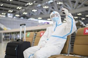 un hombre asiático lleva traje de ppe en el aeropuerto internacional, viajes de seguridad, protección covid-19, concepto de distanciamiento social foto