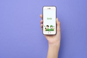 Woman hand holding Smart Phone with Grab logo on Apple iPhone SE photo