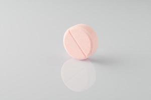 pink medical ascorbic pill on a light background with reflection photo