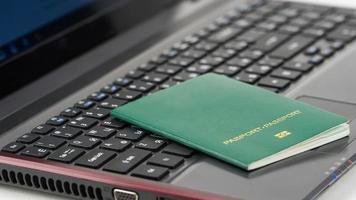 green passport on the laptop keyboard. Online registration photo