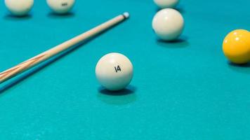 Green billiard table with white balls and cue. Closeup photo