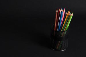 set of colored pencils in a basket on a black background, isolated. back to school photo