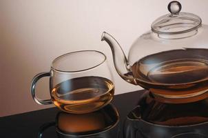 transparent glass teapot and tea cup with reflection photo