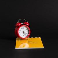 alarm clock with notepad and colored pencils on black background, isolated. back to school. great ideas photo