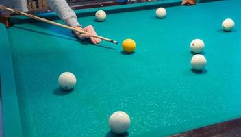 Green billiard table with white balls. Young man playing billiards photo