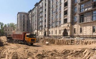 en el sitio de construcción, la excavadora carga la tierra en el camión volquete foto