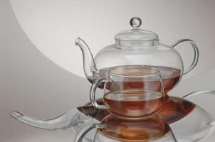 transparent teapot with teacup on the reflective surface. distorted reflection