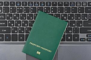 green passport on the laptop keyboard. Online registration. Top view photo