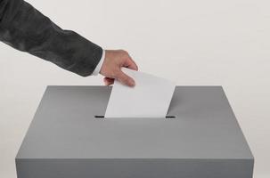 Gray ballot box. Presidential and parliamentary elections. The voter throws the ballot into the ballot box photo