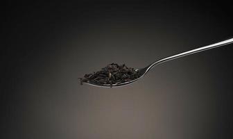 one spoon with tea leaves closeup on a dark gray background photo