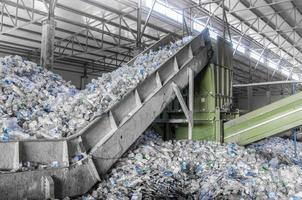 Escalator with a pile of plastic bottles at the factory for  recycling. PET recycling plant photo