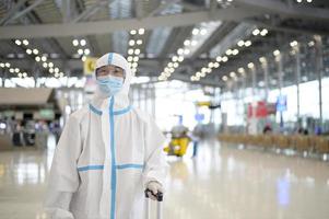 An Asian man is wearing ppe suit in International airport , Safety travel , covid-19 protection , social distancing concept photo