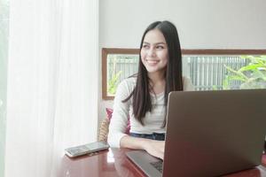una joven está trabajando con su computadora portátil en una cafetería foto