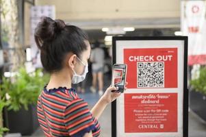 people hand is holding smartphone with Thaichana campaign of Thailand for COVID-19 prevention in shopping center photo