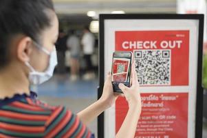 la mano de la gente sostiene un teléfono inteligente con la campaña thaichana de tailandia para la prevención de covid-19 en el centro comercial foto