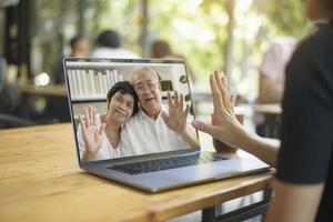 A young woman is using computer laptop to Video calling or Webcam to grandparent ,  telecommunications technology , parenthood family concept photo